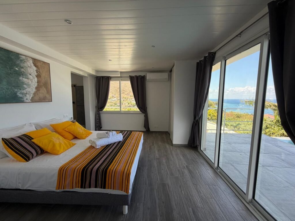 Suite parentale de la Villa Marine Blue avec accès direct à la terrasse, à la piscine à débordement et vue mer panoramique.